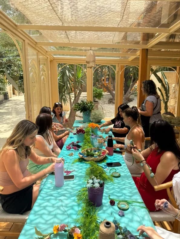 SheFlows participants making flower arrangements together around a workshop table.